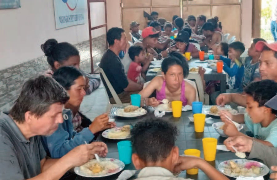large group of people seated at a table with food to eat a meal in Ecuador